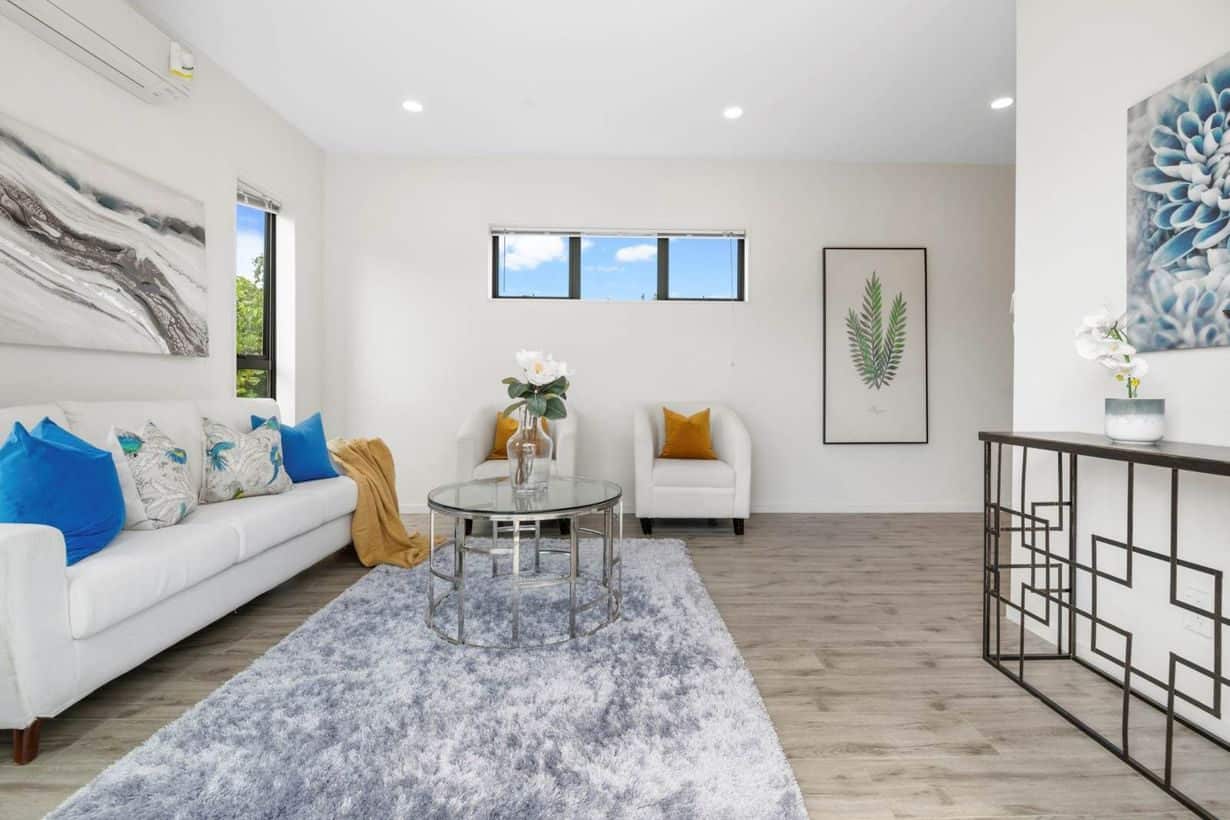 Staged living room with a white sofa and timber-look flooring, Albany Village