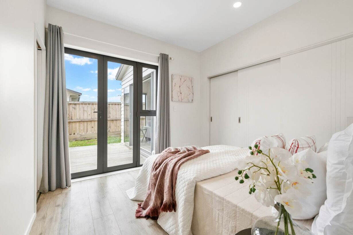 Bedroom opening through a sliding door onto a fenced courtyard, Albany Village
