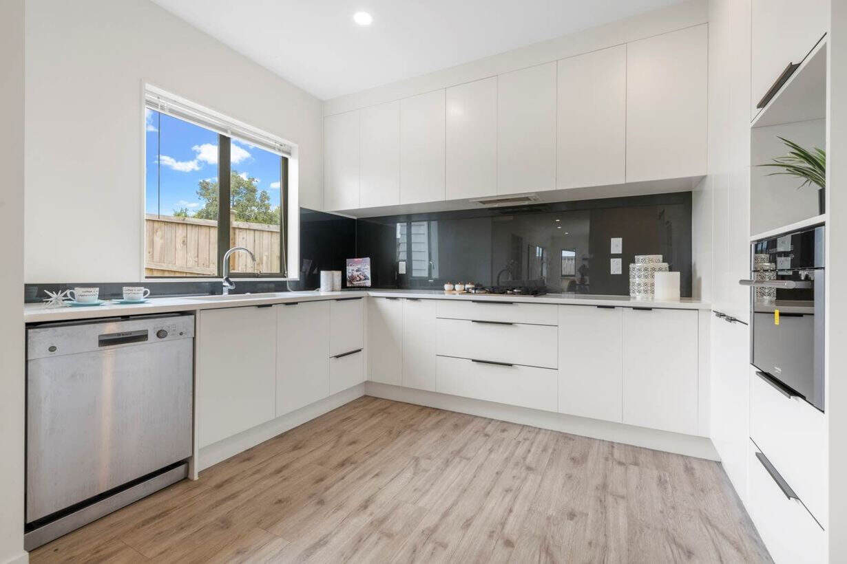 L-shaped white kitchen with a dark glass splashback, wall oven and dishwasher, Albany Village