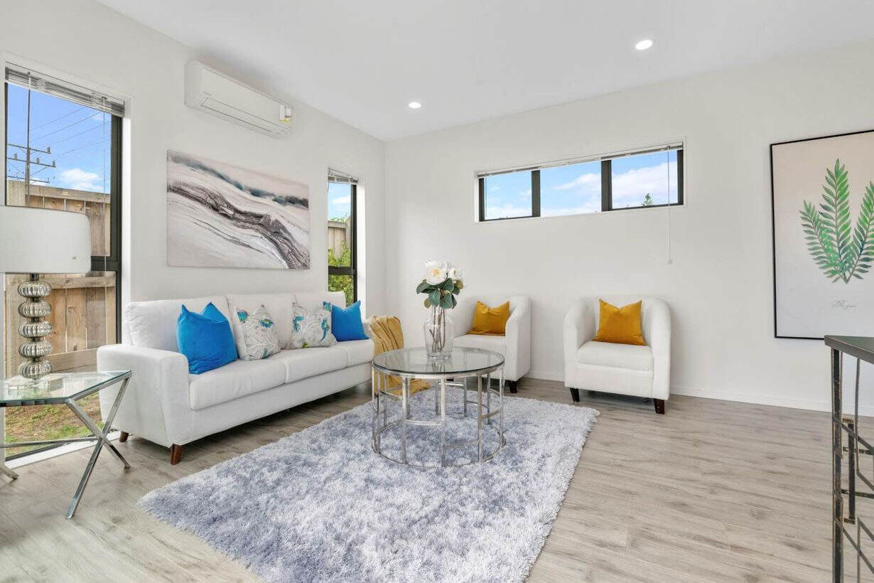 Living room with a heat pump, white sofa and armchairs on a grey rug, Albany Village