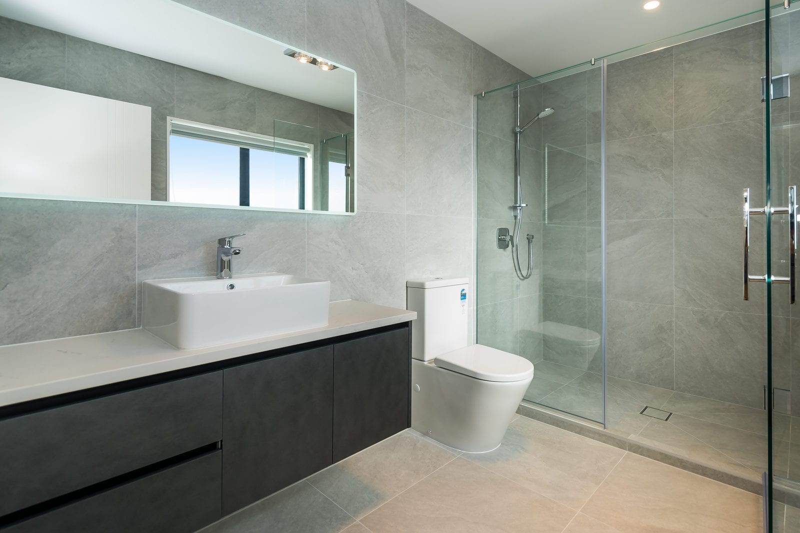 Bathroom with a dark floating vanity, wall-hung toilet and a glazed shower, Orewa
