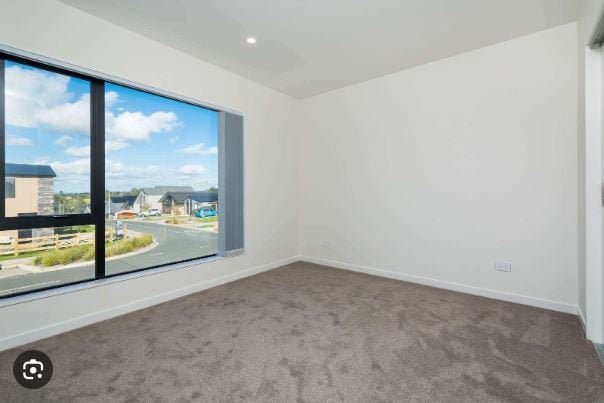 Empty carpeted room with a large corner window looking over the neighbourhood, Orewa