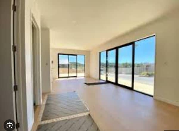 Empty open-plan living space with full-height sliding doors onto a deck, Orewa