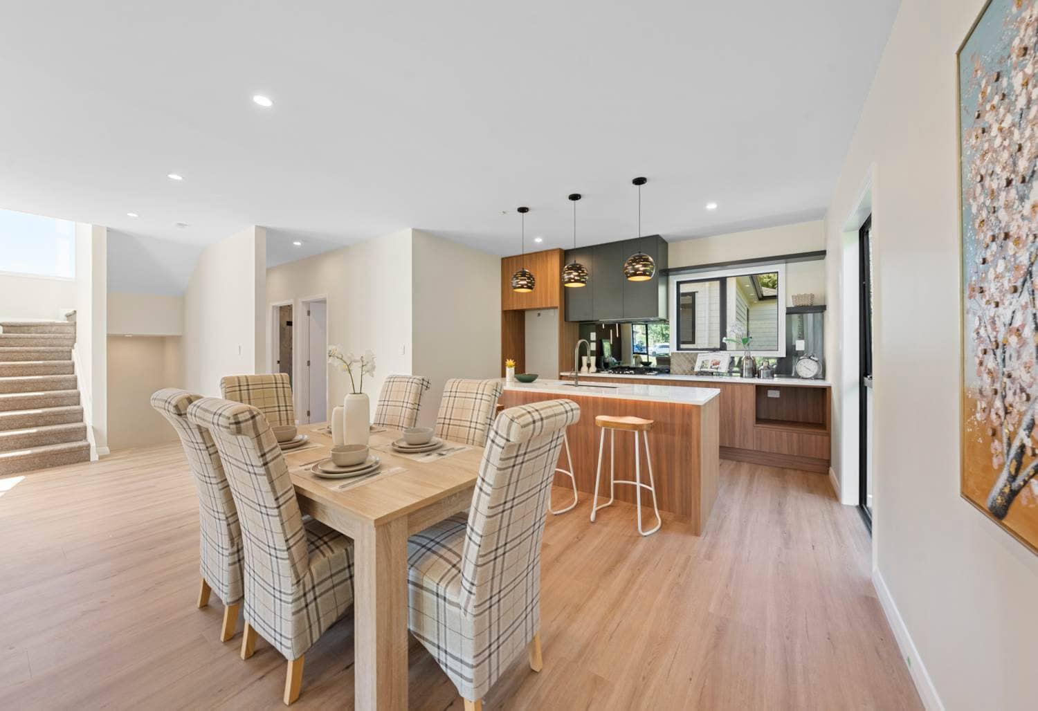 Open-plan dining and kitchen with a long table and a raised breakfast bar, Browns Bay