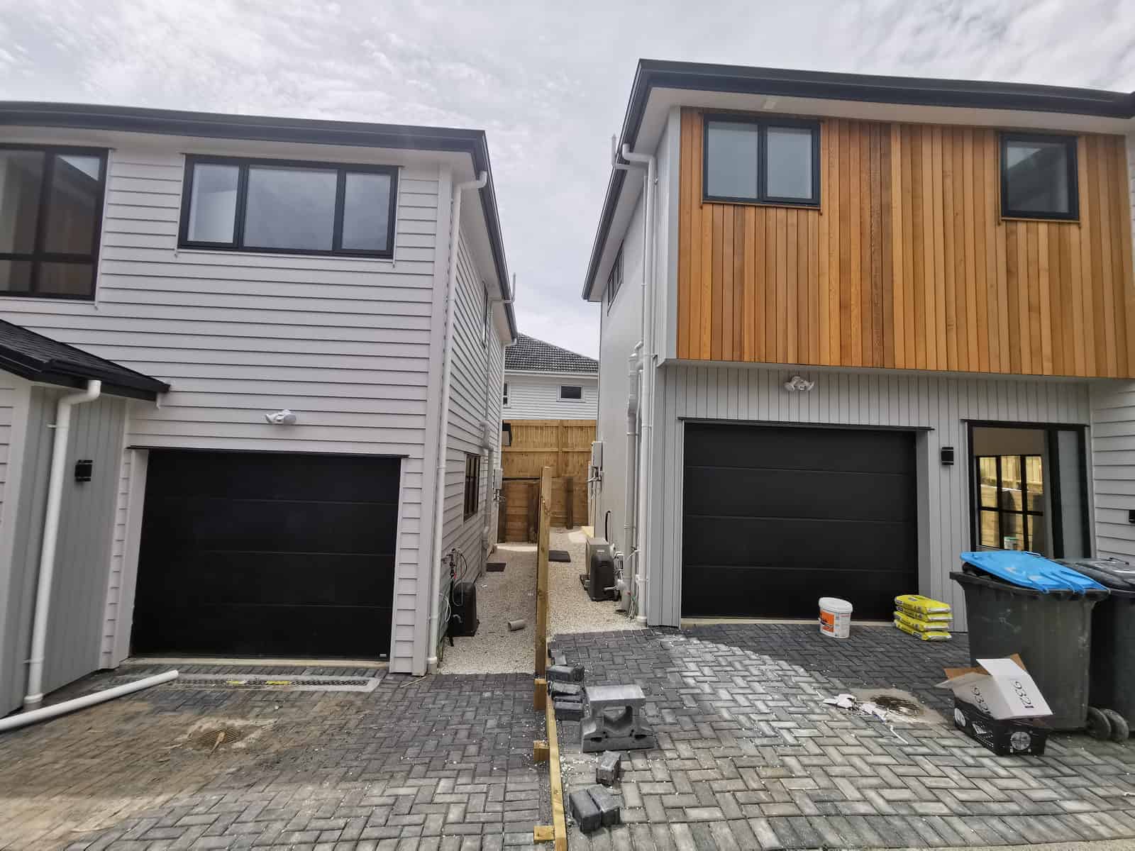 Two newly built houses side by side on a shared paved driveway, Blockhouse Bay