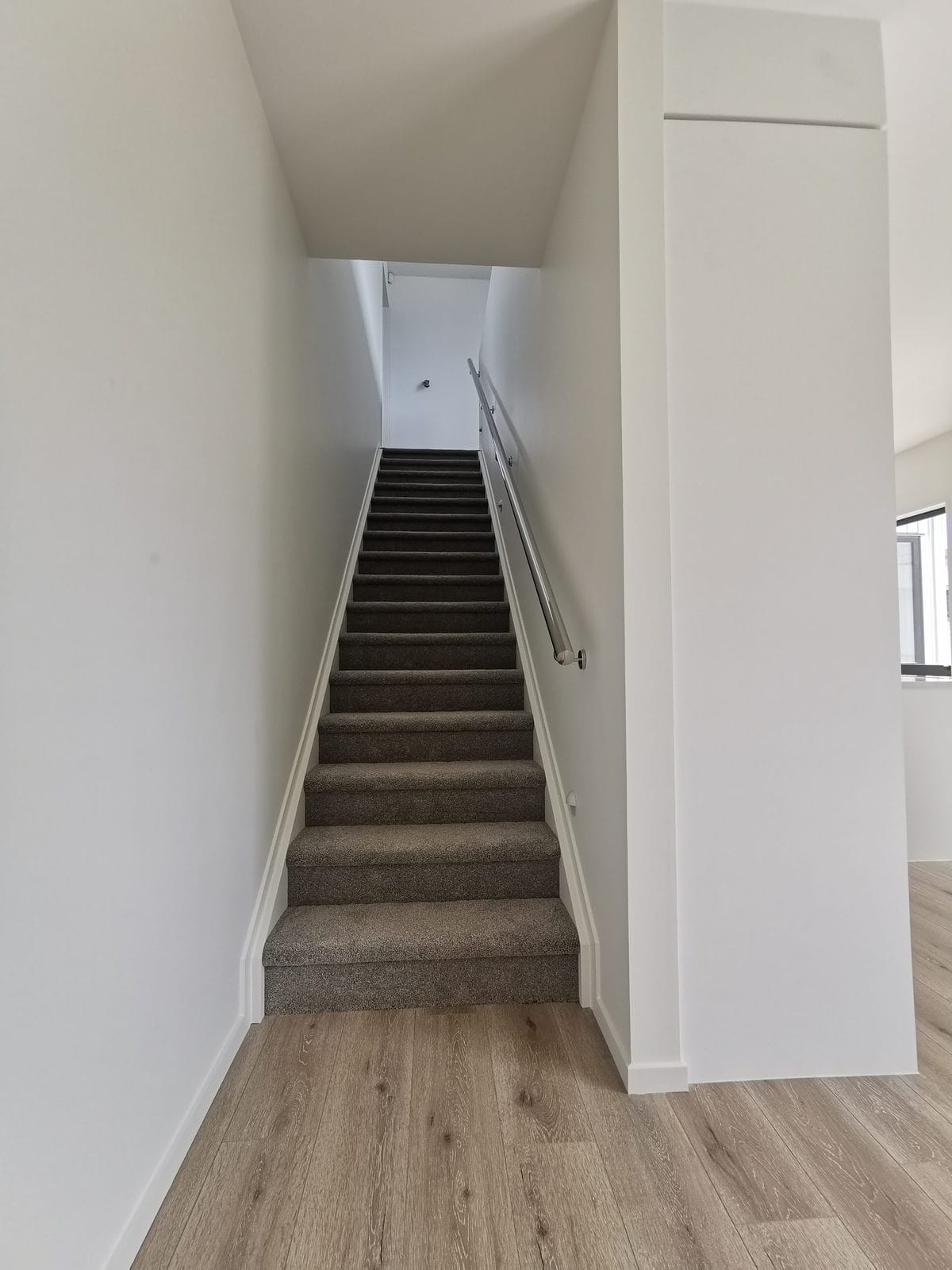 Carpeted stair rising between plasterboard walls with a slim handrail, Blockhouse Bay