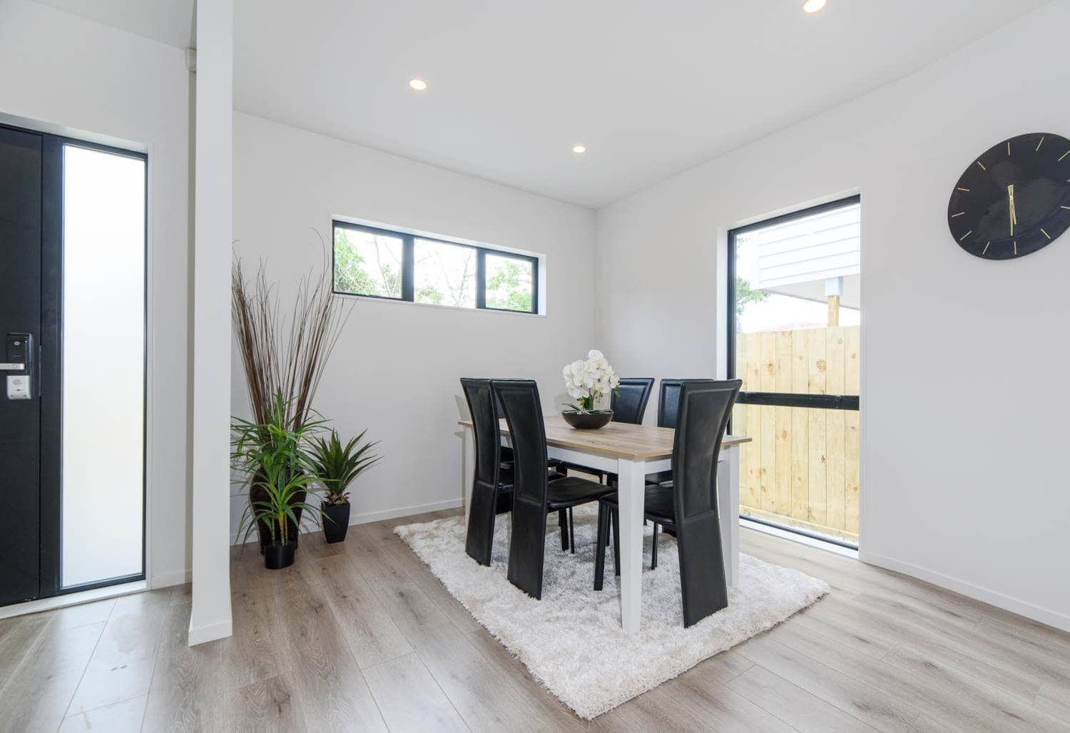 Dining table beside a sliding door onto a fenced courtyard, Blockhouse Bay