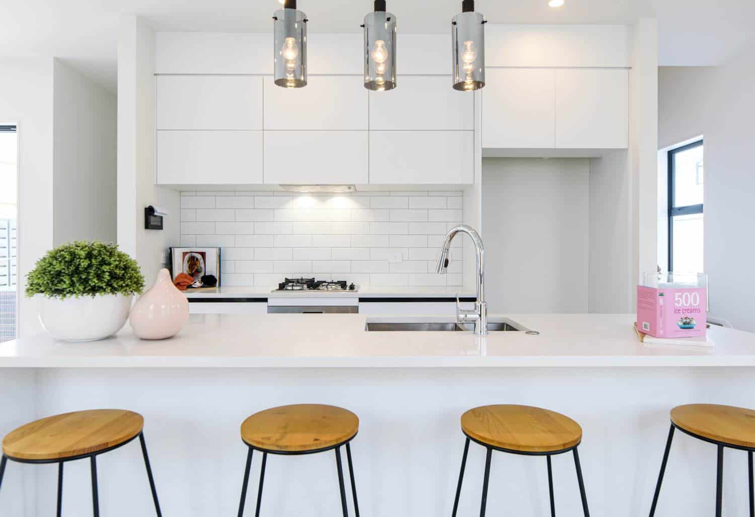 White kitchen with a subway-tiled splashback, pendant lights and timber bar stools, Blockhouse Bay