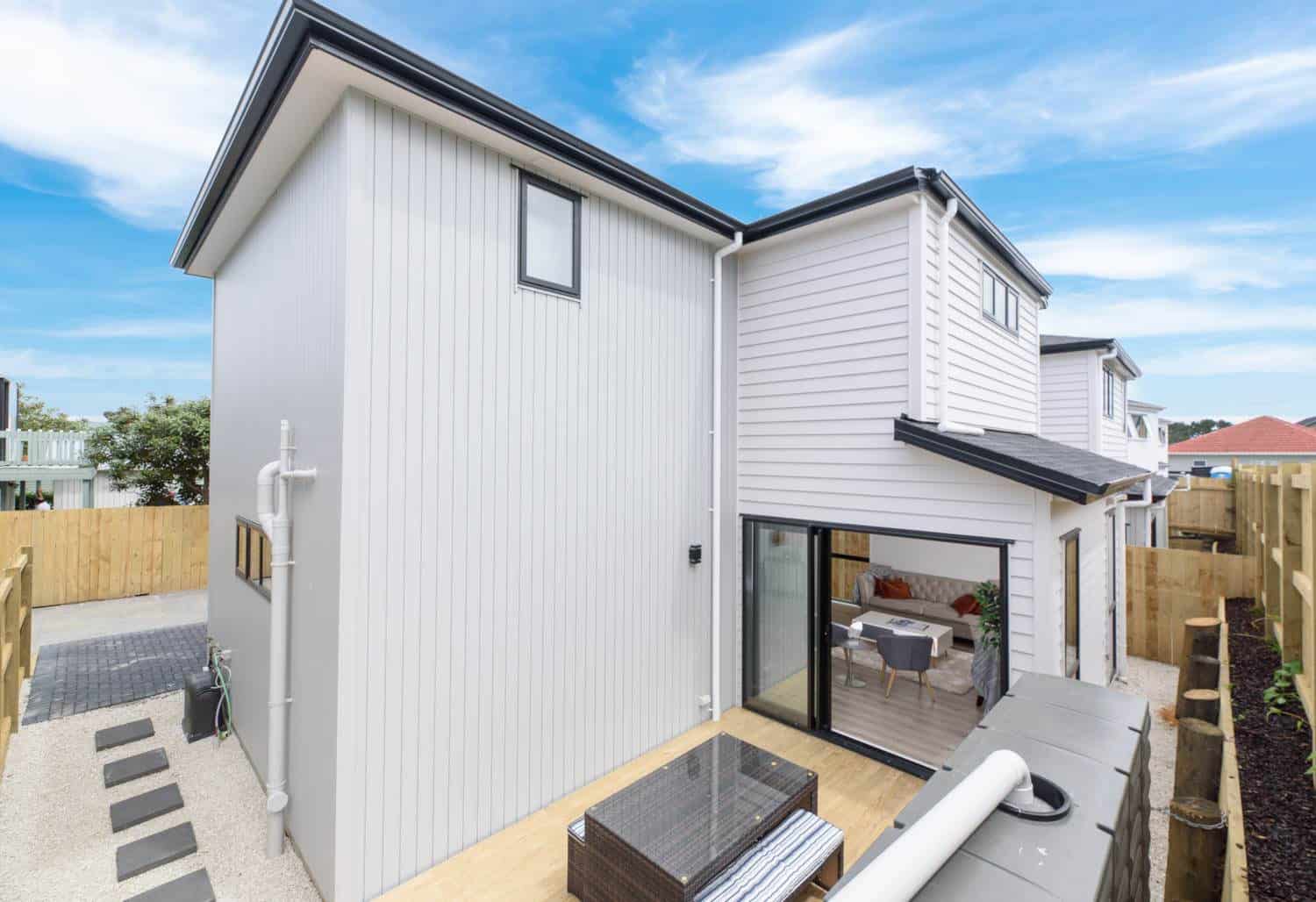 Rear of a new house with a sliding door onto a small paved yard, Blockhouse Bay