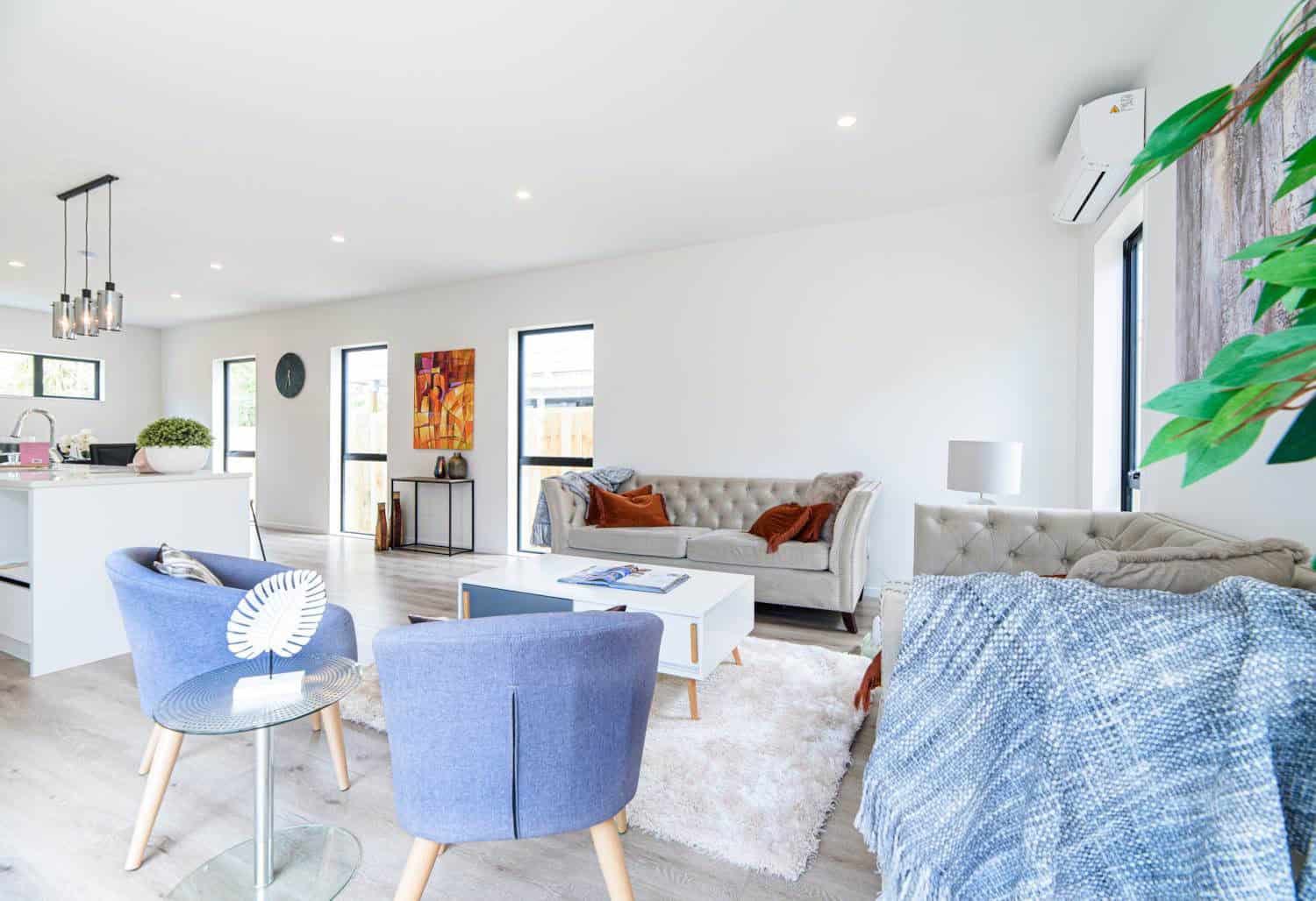 Living area with blue armchairs and a sofa alongside the kitchen, Blockhouse Bay