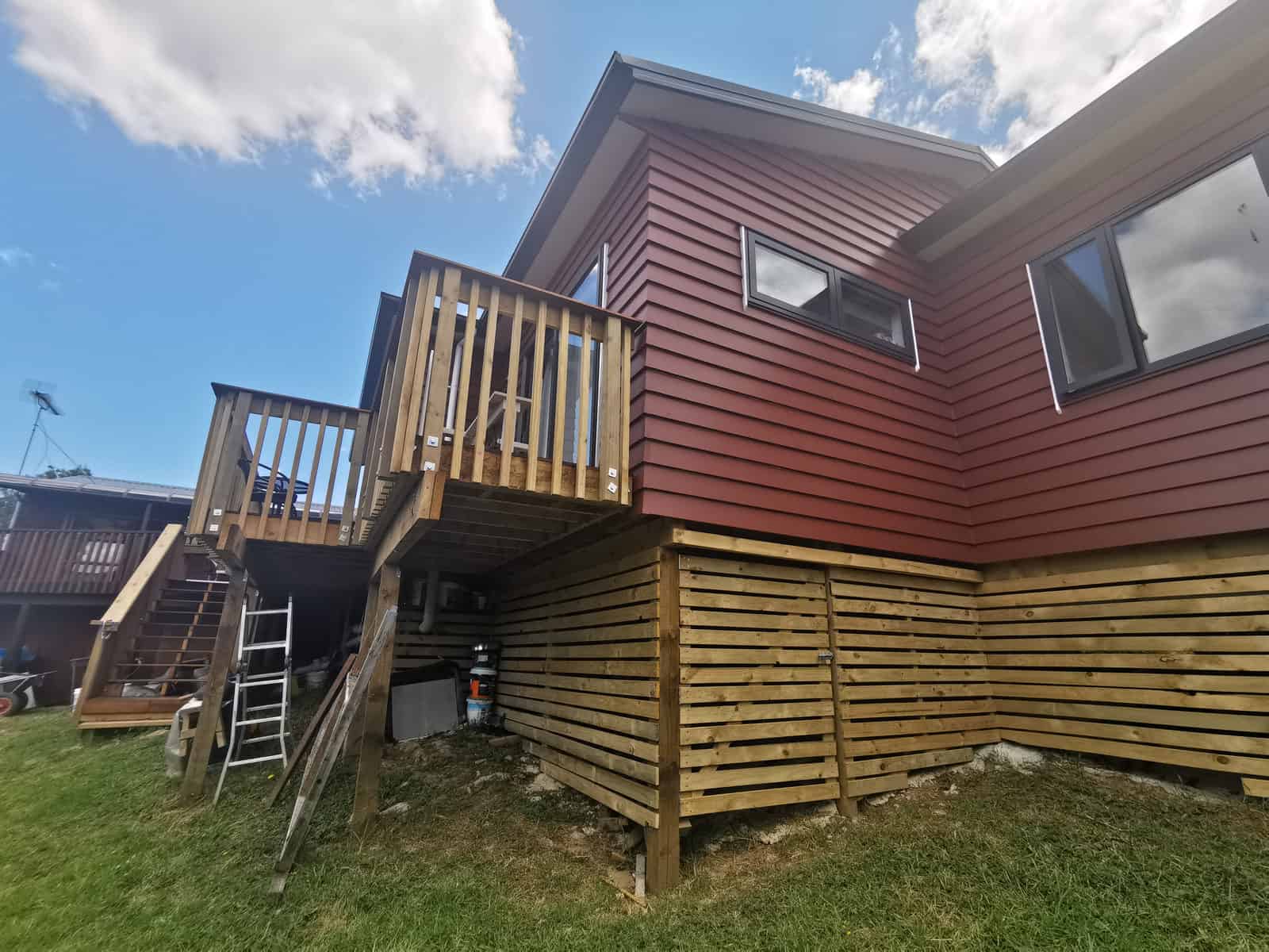 Extended elevation with new red weatherboard cladding and a timber batten skirt, Botany Downs