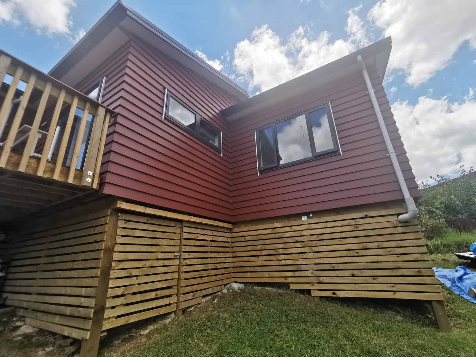 New red weatherboard cladding and windows across the extended elevation, Botany Downs