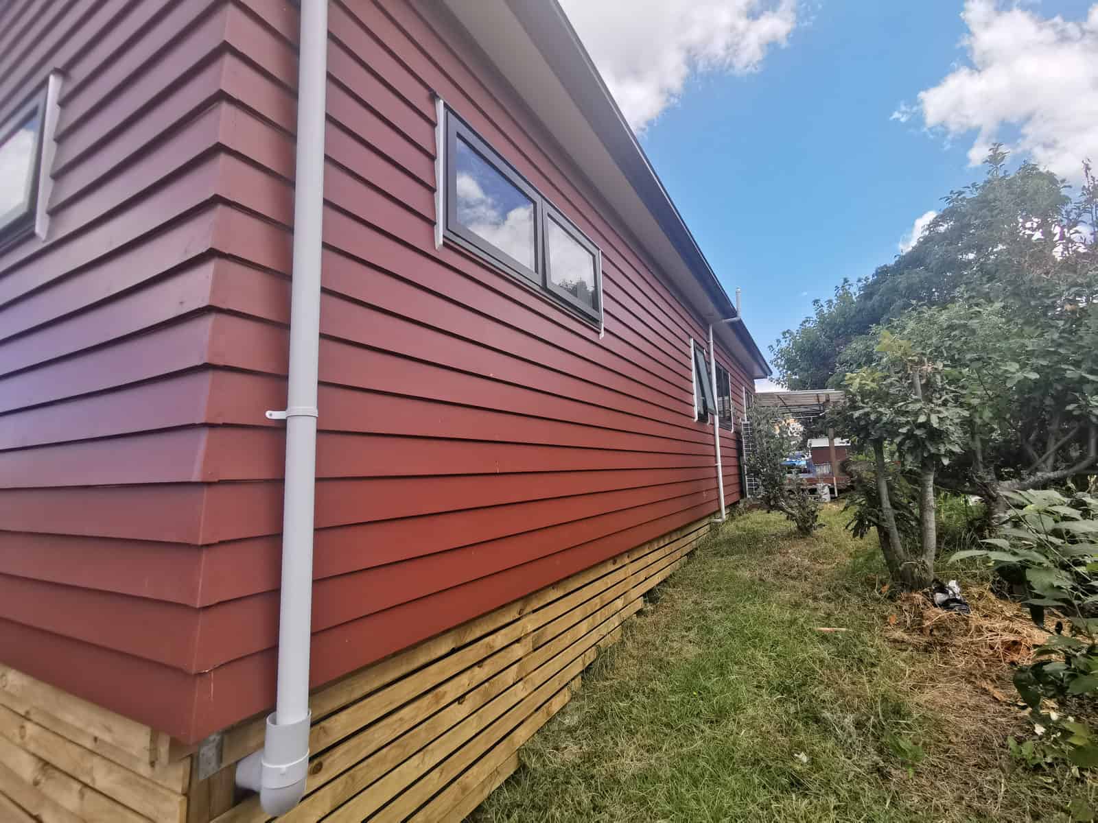 Side elevation in new red weatherboard above an unpainted timber batten base, Botany Downs