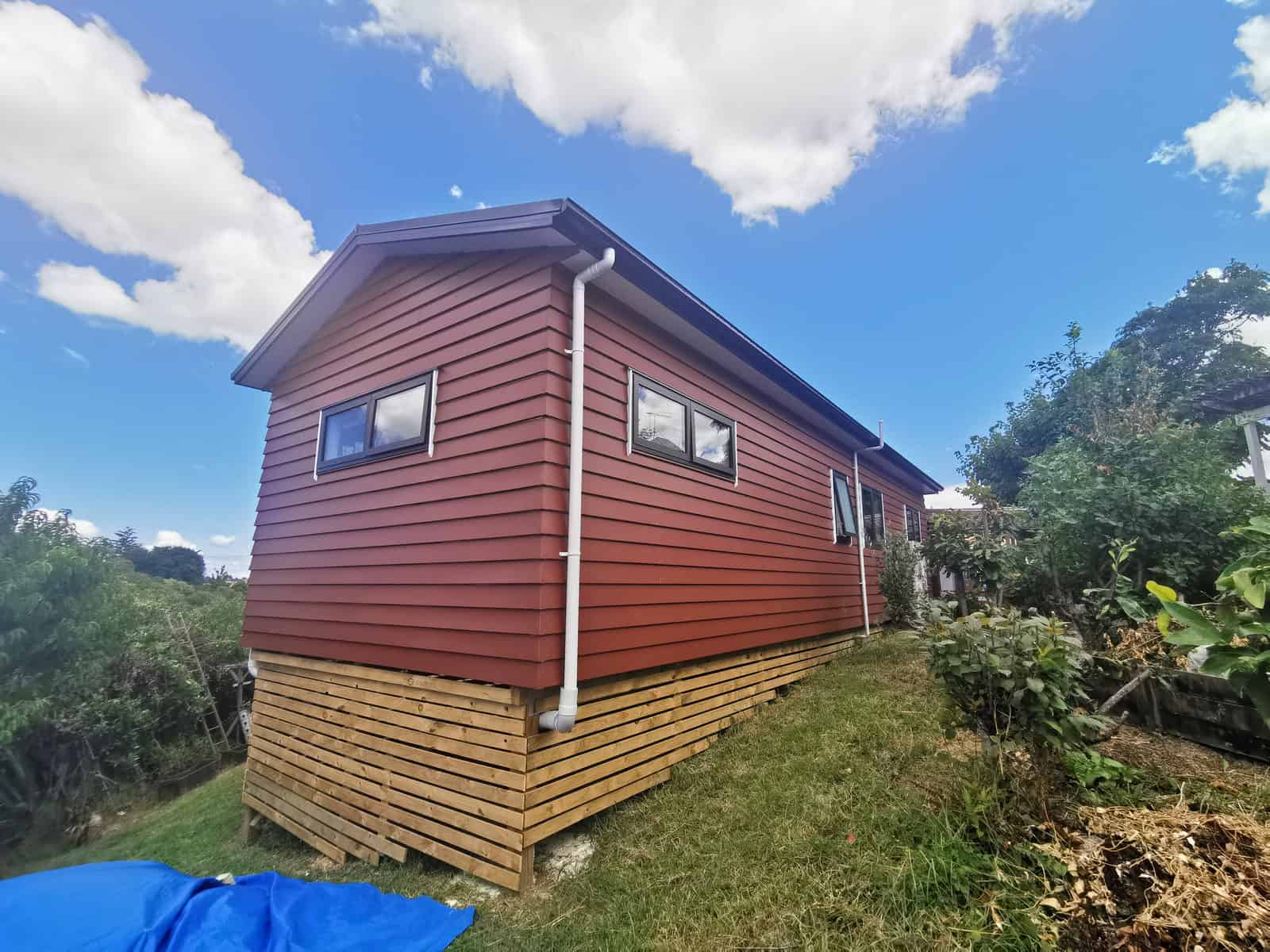 Corner of the extension in new red cladding raised above a timber batten skirt, Botany Downs