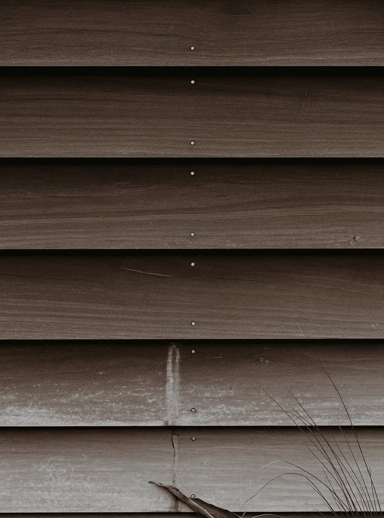 Close-up of dark-stained horizontal timber weatherboards and their fixings on a coastal house