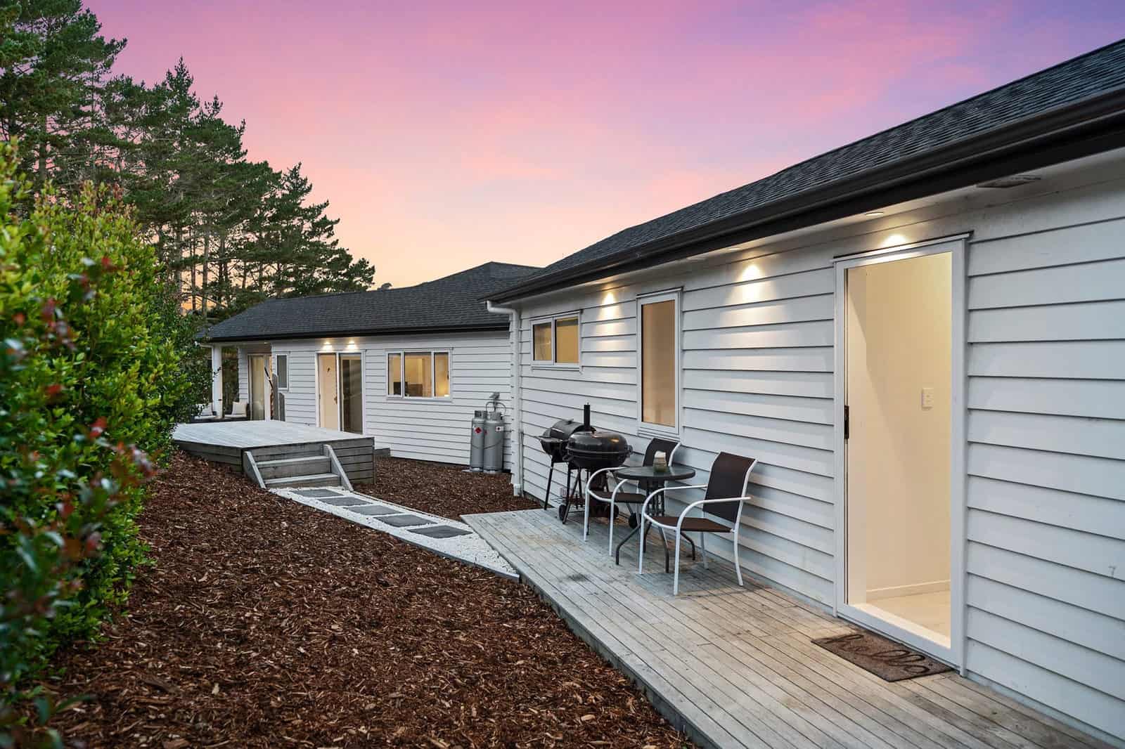 Timber deck running along the minor dwelling at dusk with outdoor seating, Coatesville
