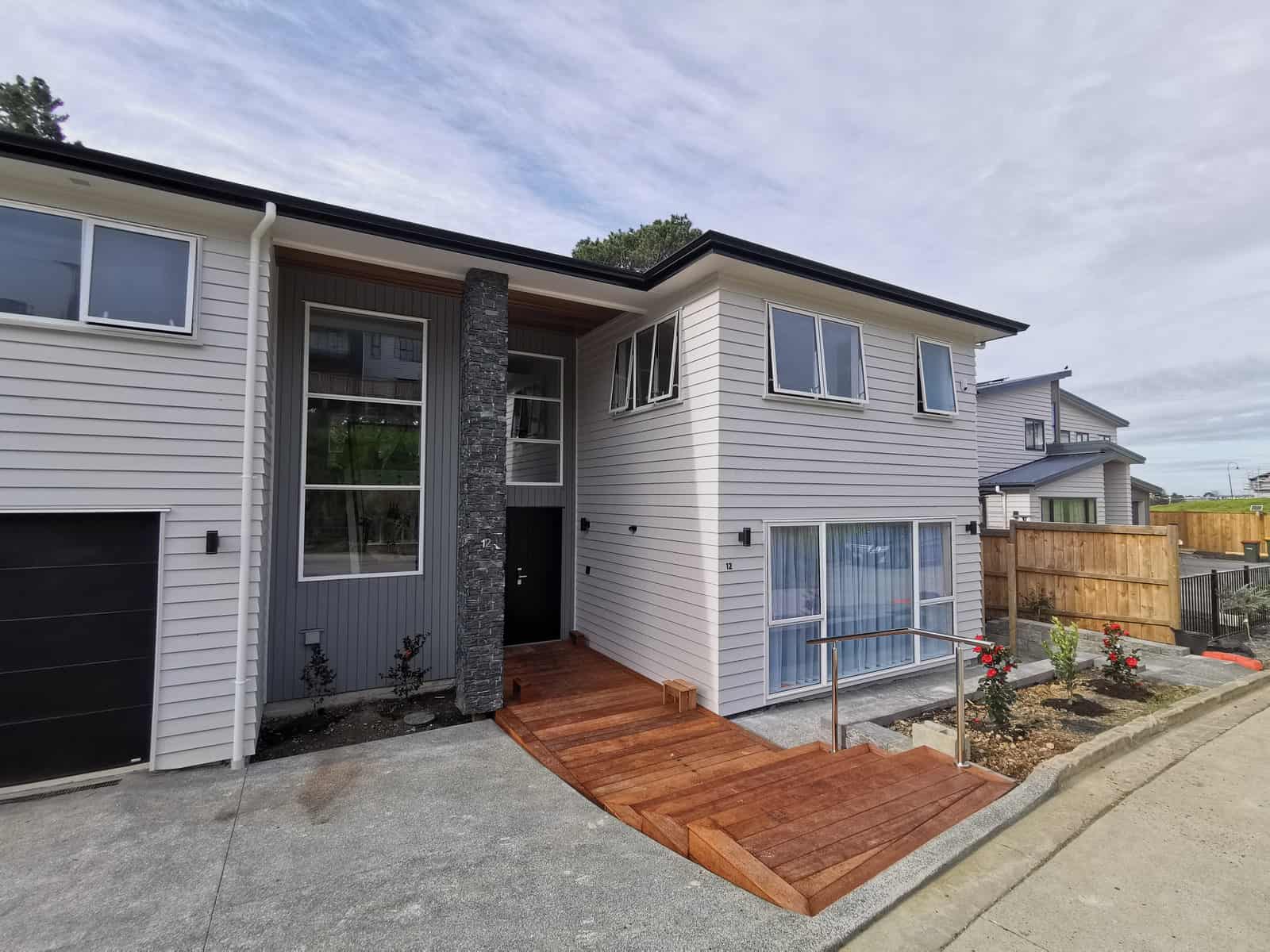 Entry elevation with a schist feature wall and a timber deck at the front door, Albany