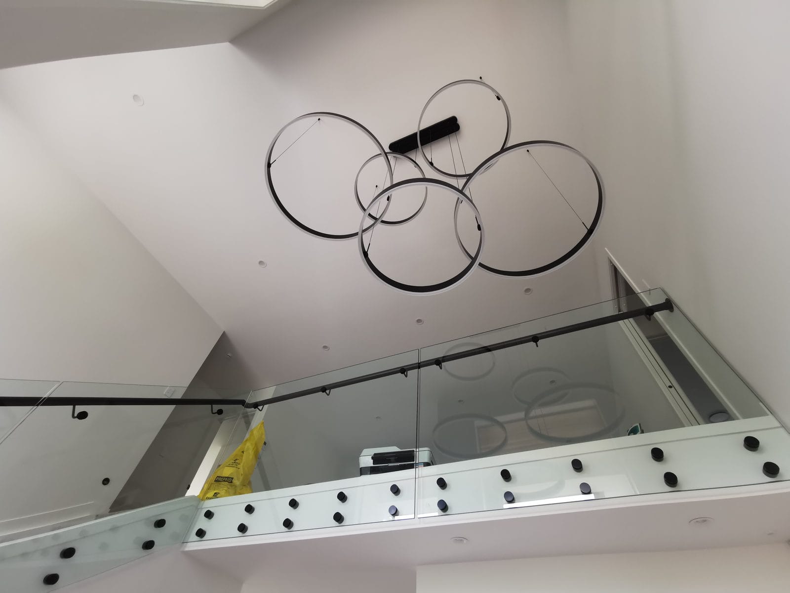 Double-height void with a glass balustrade and a circular pendant light, Albany