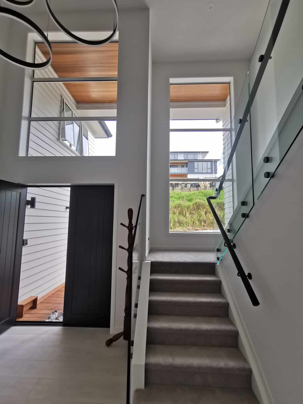 Entry with the stair rising past a glass balustrade to the upper level, Albany