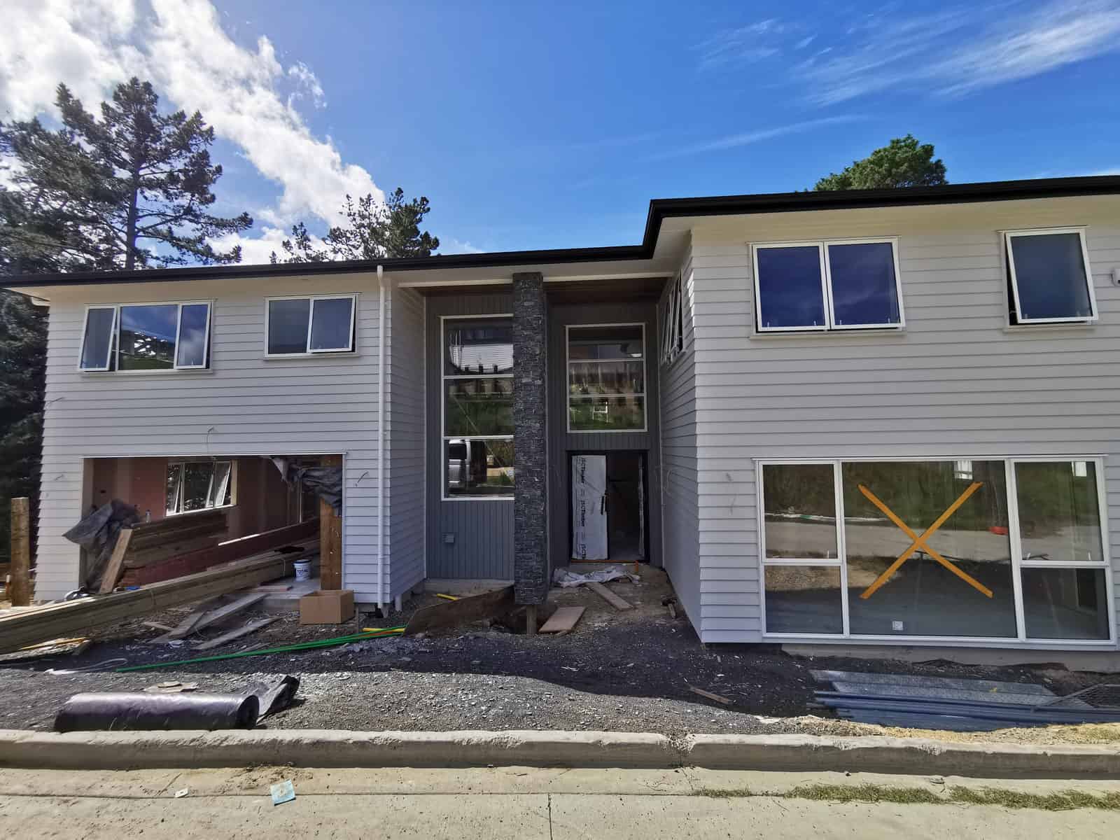 Front of the house late in the build with a schist feature wall and taped glazing, Albany