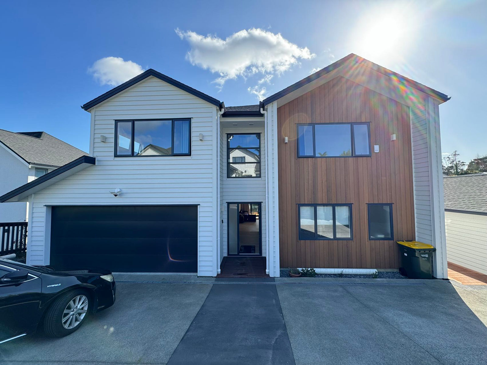 Two-storey house in white weatherboard and timber cladding with a double garage, Greenhithe