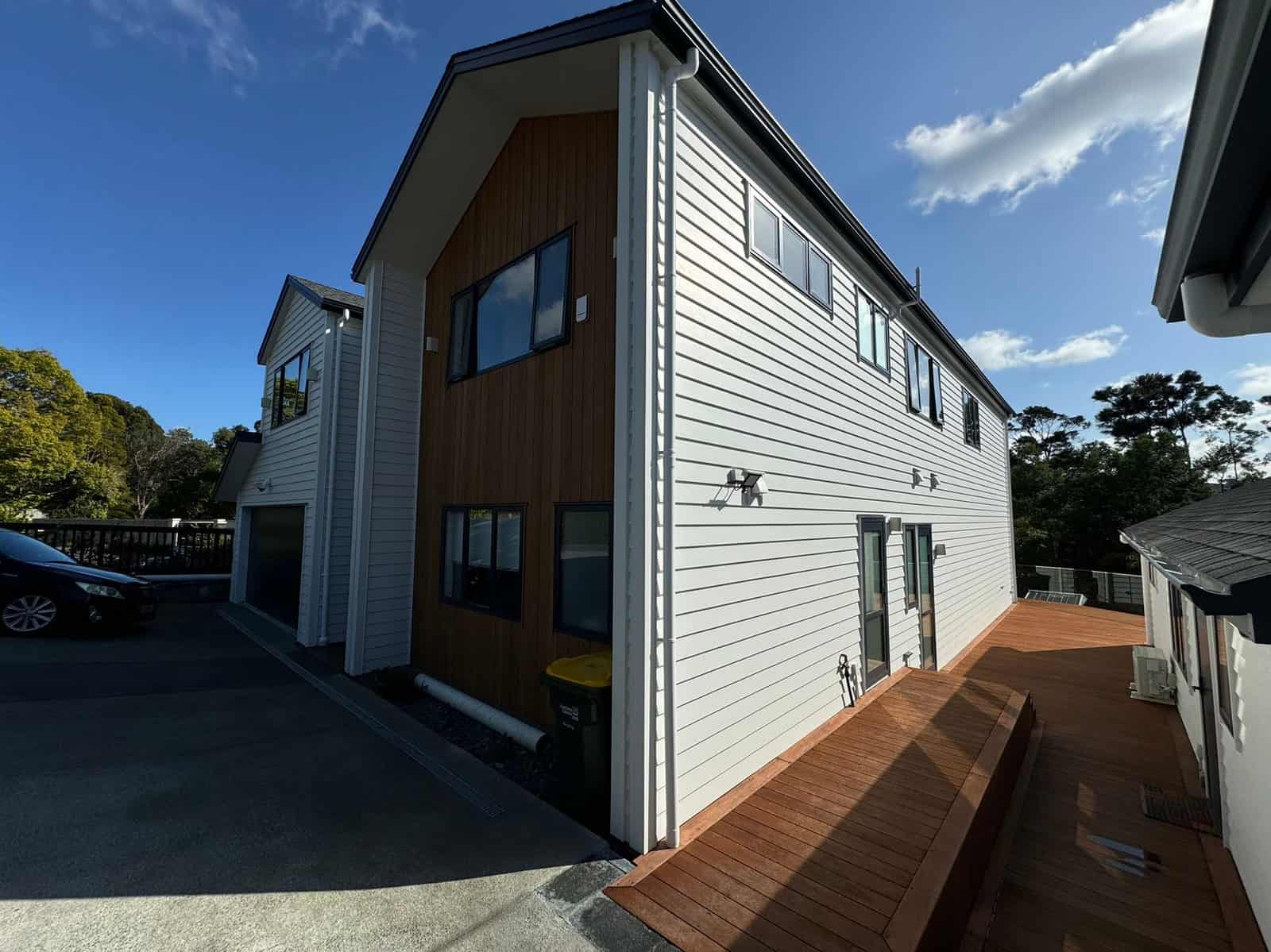 Side elevation of the house in white weatherboard and timber with the deck alongside, Greenhithe