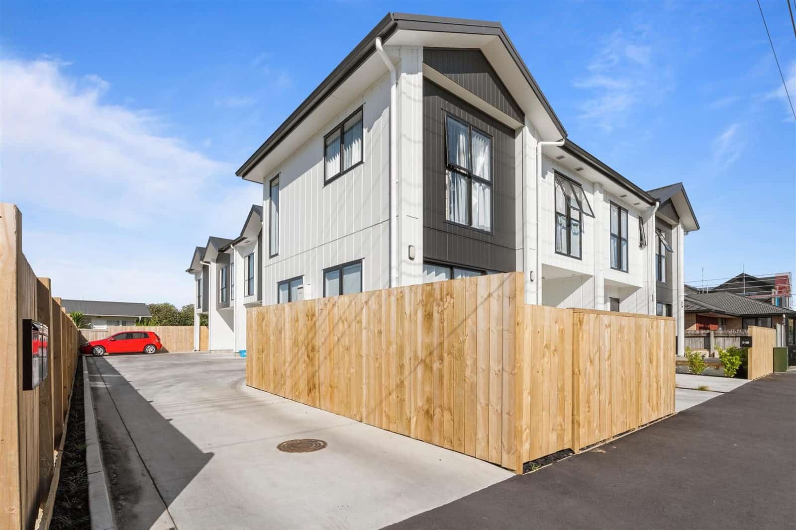Completed terraced houses with timber boundary fencing along a shared drive, Hamilton