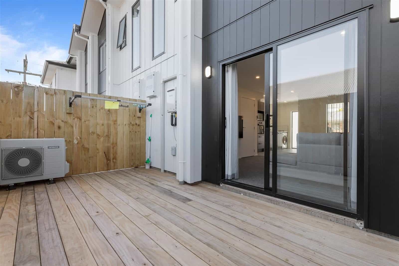 Private deck off a terraced unit with a heat pump and sliding door, Hamilton