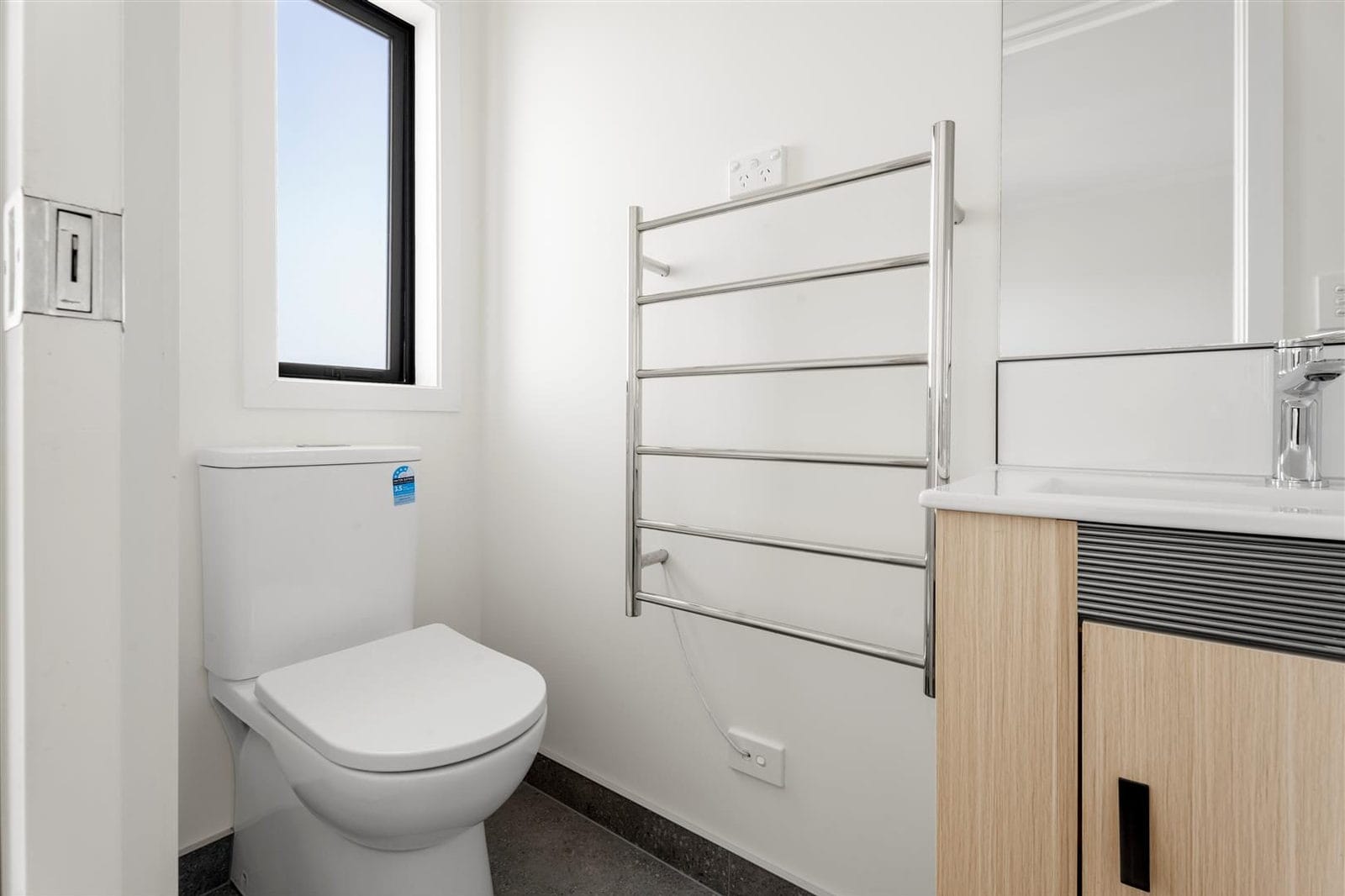 Bathroom with a wall-hung toilet, heated towel rail and timber vanity, Hamilton