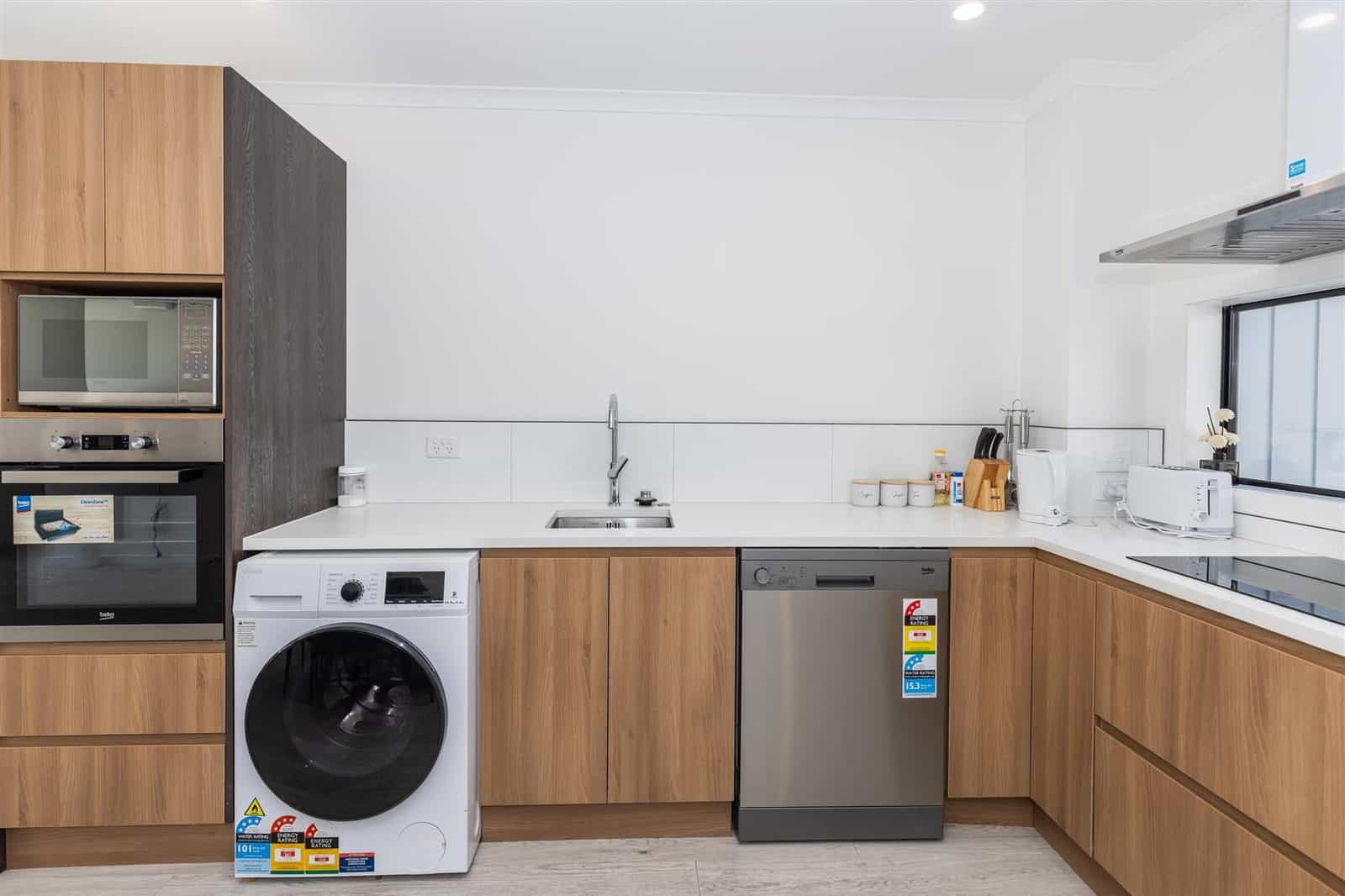 Kitchen with timber cabinetry, wall oven, washing machine and dishwasher, Hamilton