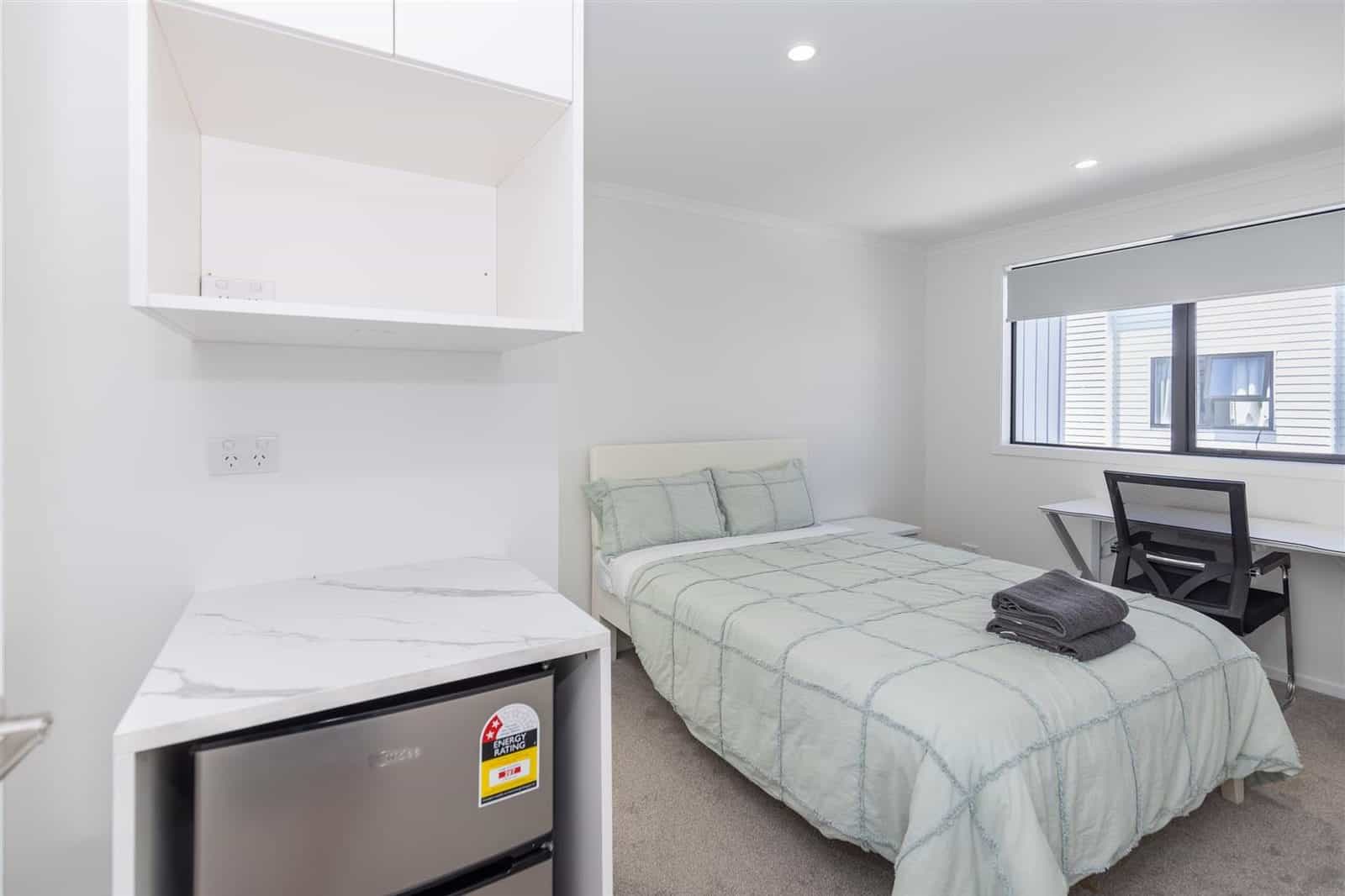Bedroom with a kitchenette alongside the bed and a desk under the window, Hamilton