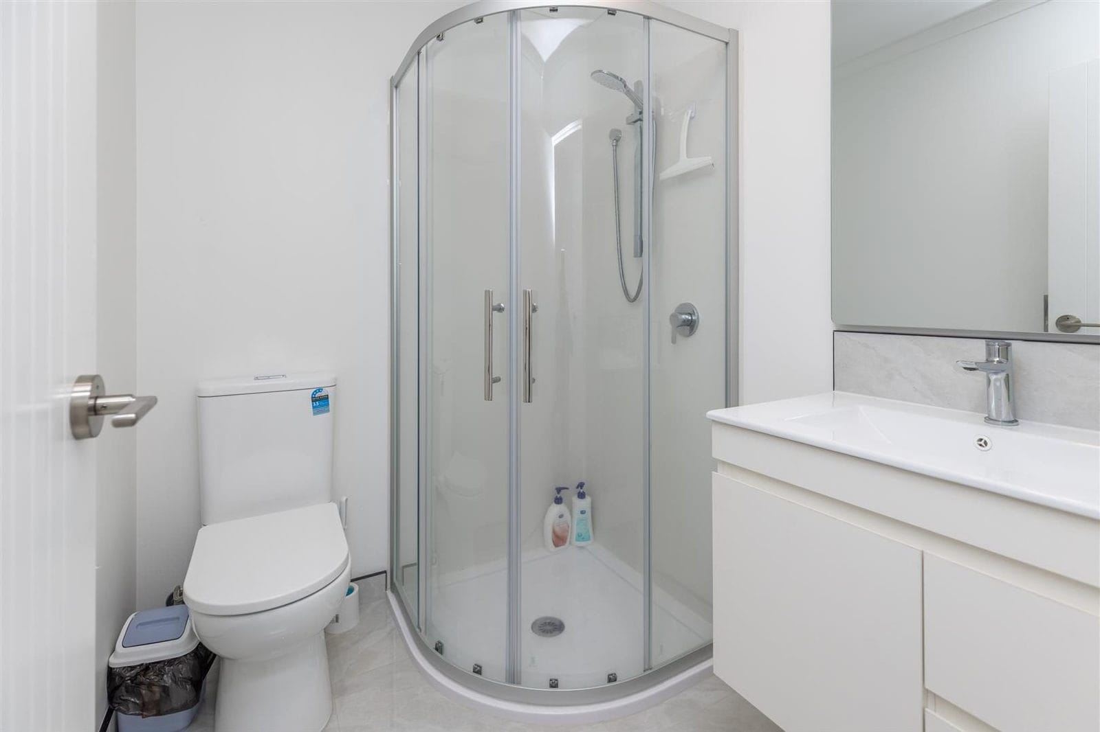 Bathroom with a corner shower, toilet and white vanity, Hamilton