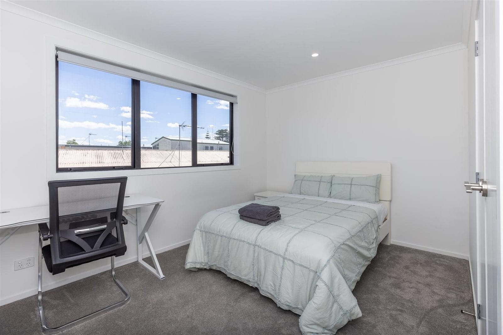 Bedroom with a desk under a wide window and a mirrored wardrobe, Hamilton