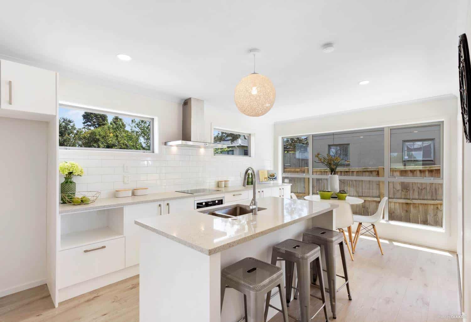 White kitchen with an island, pendant light and bar stools, Te Atatu South