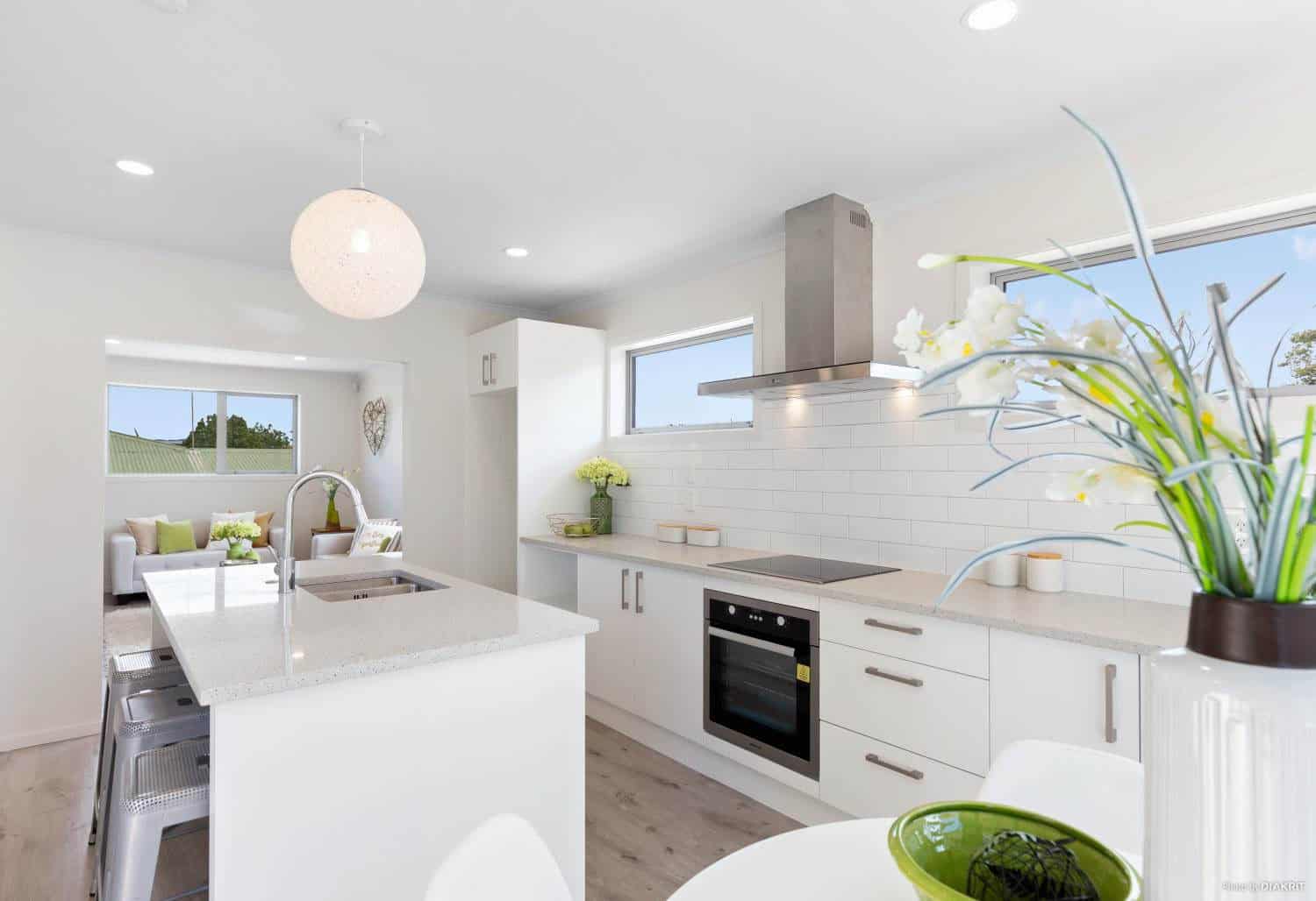 Kitchen with a stainless rangehood, wall oven and island bench, Te Atatu South