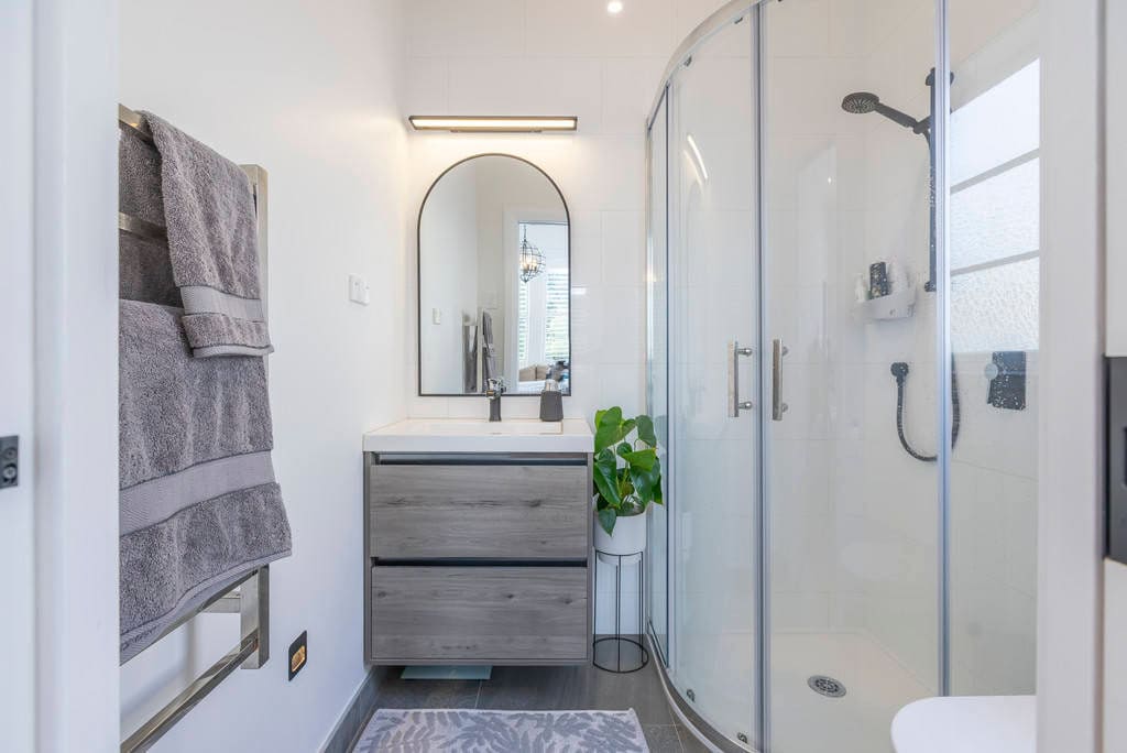 Bathroom with a floating vanity, arched mirror and a glazed corner shower, Kingsland