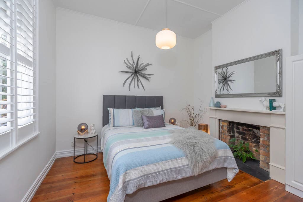 Bedroom with plantation shutters and a brick fireplace behind the bed, Kingsland