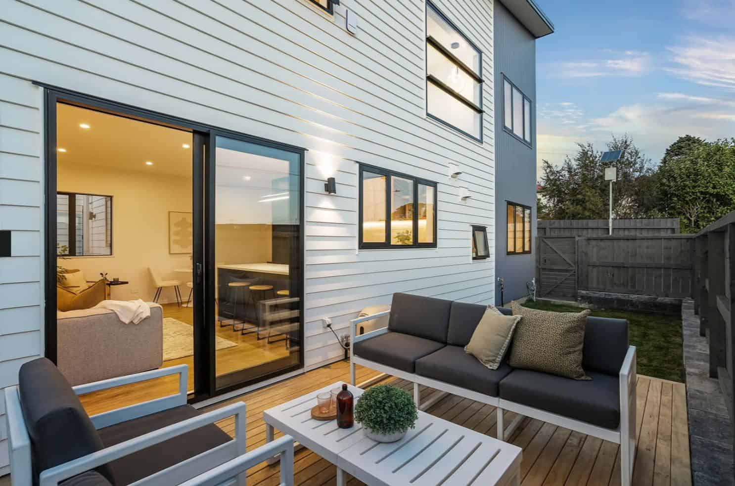 Private deck with outdoor seating beside the sliding doors at dusk, Lynfield