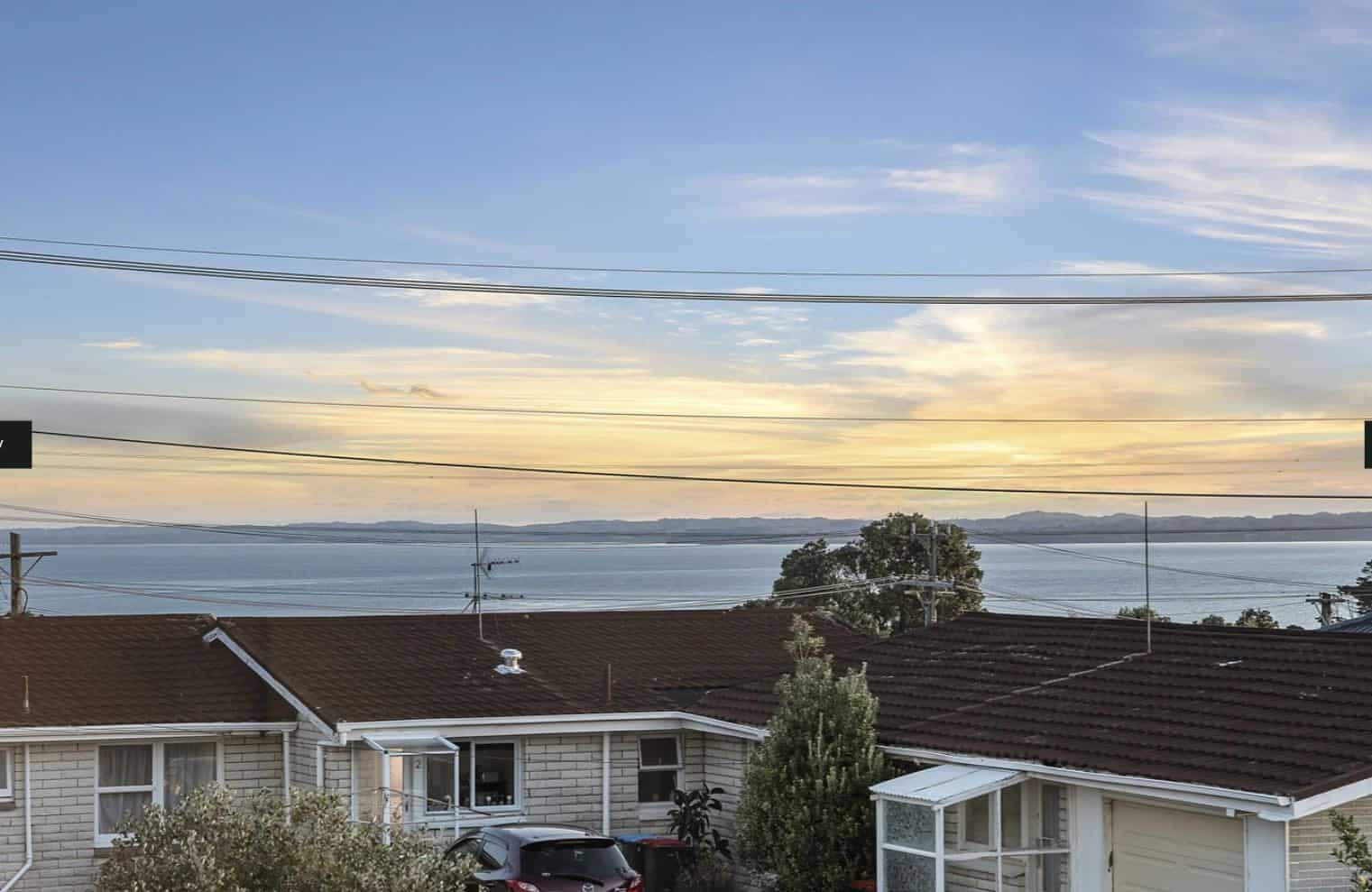 View over neighbouring rooftops to the harbour at sunset, Lynfield