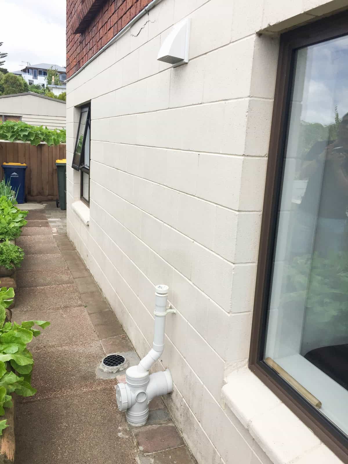 Narrow side passage between the block wall and the boundary with exposed plumbing, Mairangi Bay