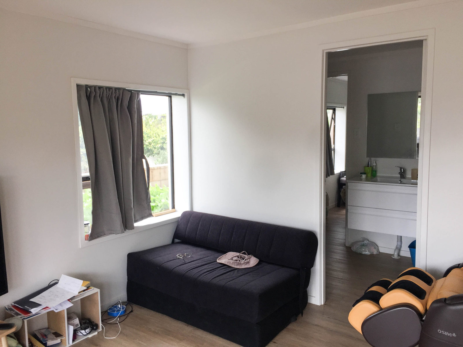 Existing living area with a sofa, curtained window and a bathroom beyond, Mairangi Bay