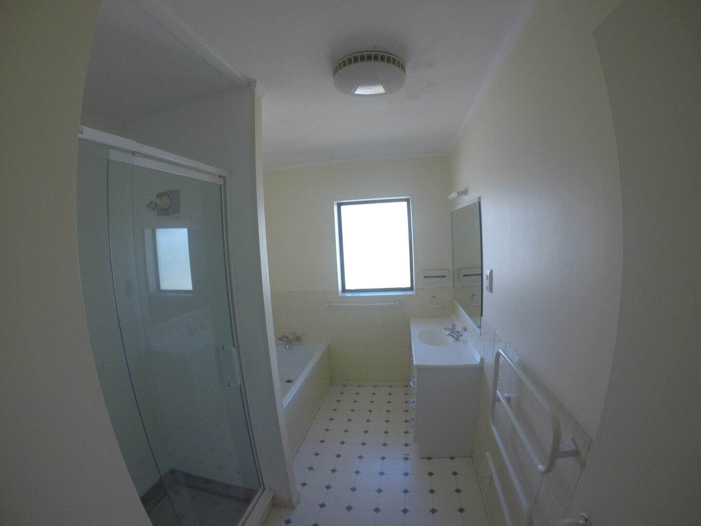 Existing bathroom with a bath, shower and vanity on a patterned vinyl floor, Mairangi Bay