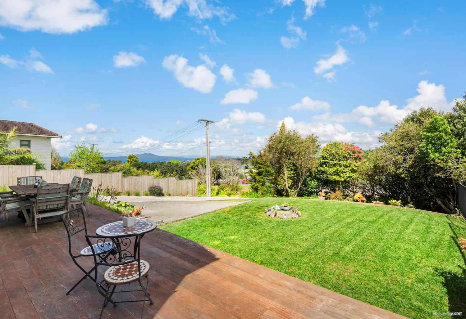 Back lawn and timber deck with outdoor furniture looking out to the gulf, Mairangi Bay