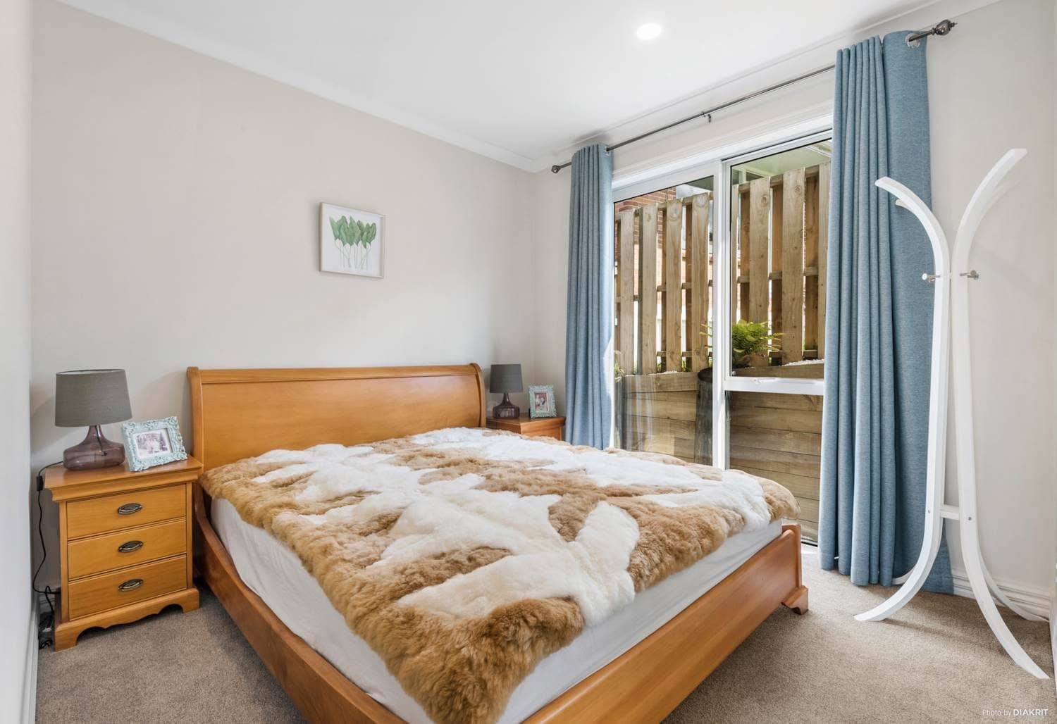 Bedroom with a sliding door to the courtyard and blue curtains, Mairangi Bay