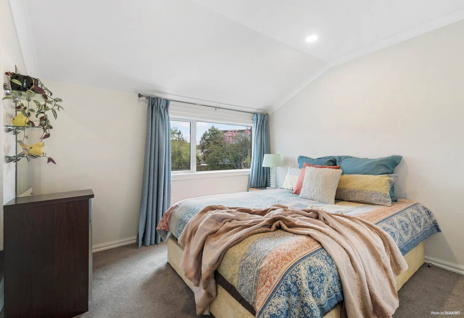 Bedroom with a tall window and blue curtains, Mairangi Bay