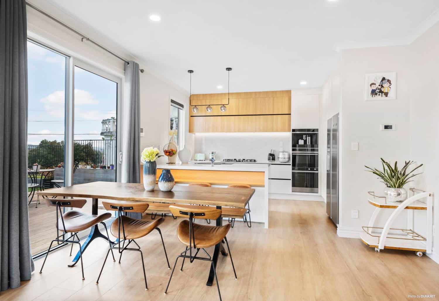 Dining table in front of a timber kitchen with sliding doors to the deck, Mairangi Bay