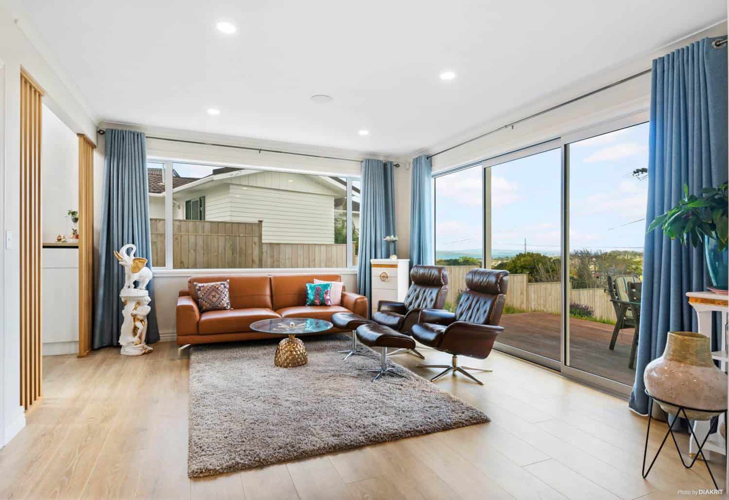Living room with a leather sofa and full-height glazing to the deck, Mairangi Bay