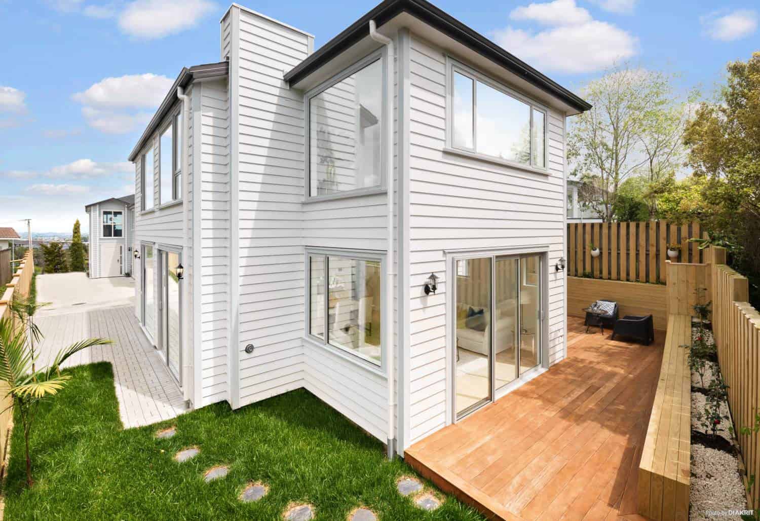 Two-storey weatherboard house with a hardwood deck and lawn, Mairangi Bay