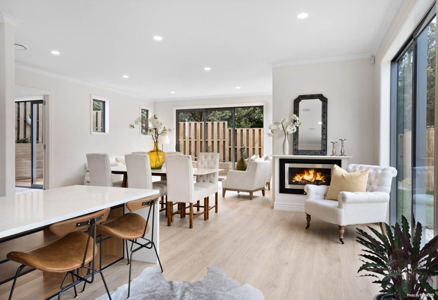 Open-plan dining and living with a gas fire and sliding doors to the deck, Mairangi Bay