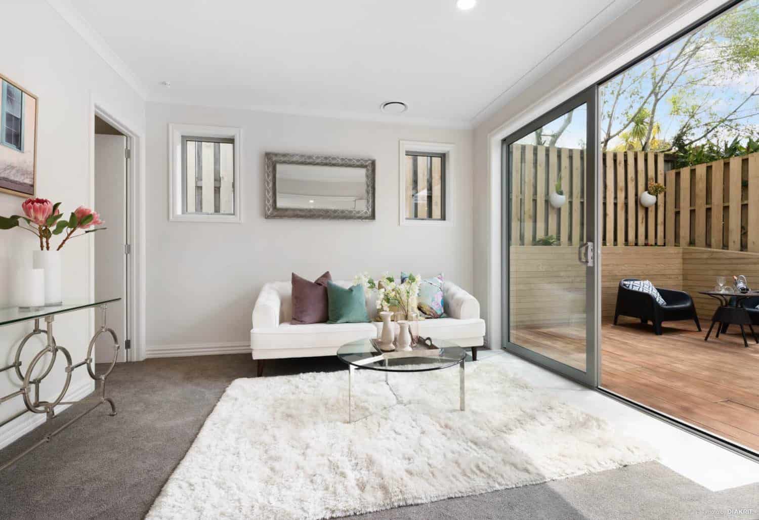 Living room with sliding doors onto the deck and a light rug, Mairangi Bay